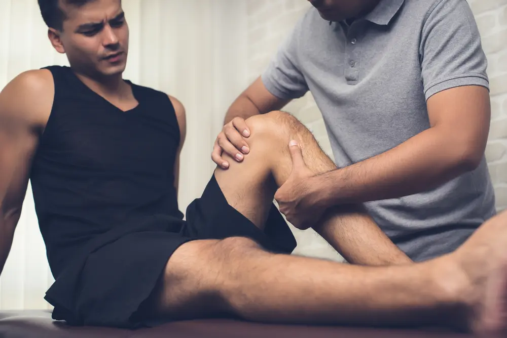 osteopathic-therapist-treating-injured-knee-of-athlete-male-patient-in-clinic-sport-physical-therapy-concept